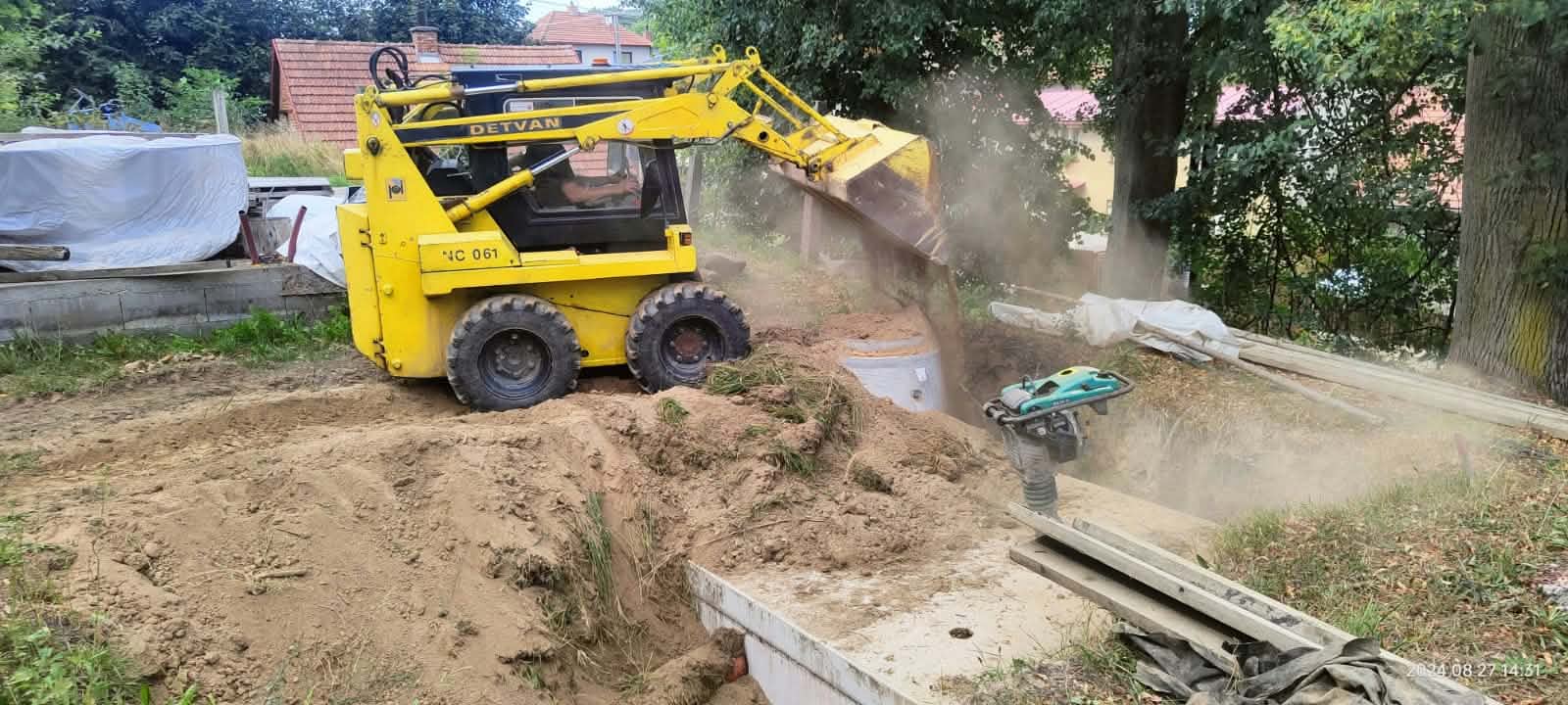 Nakladač Detvan zasypává výkop u jímky