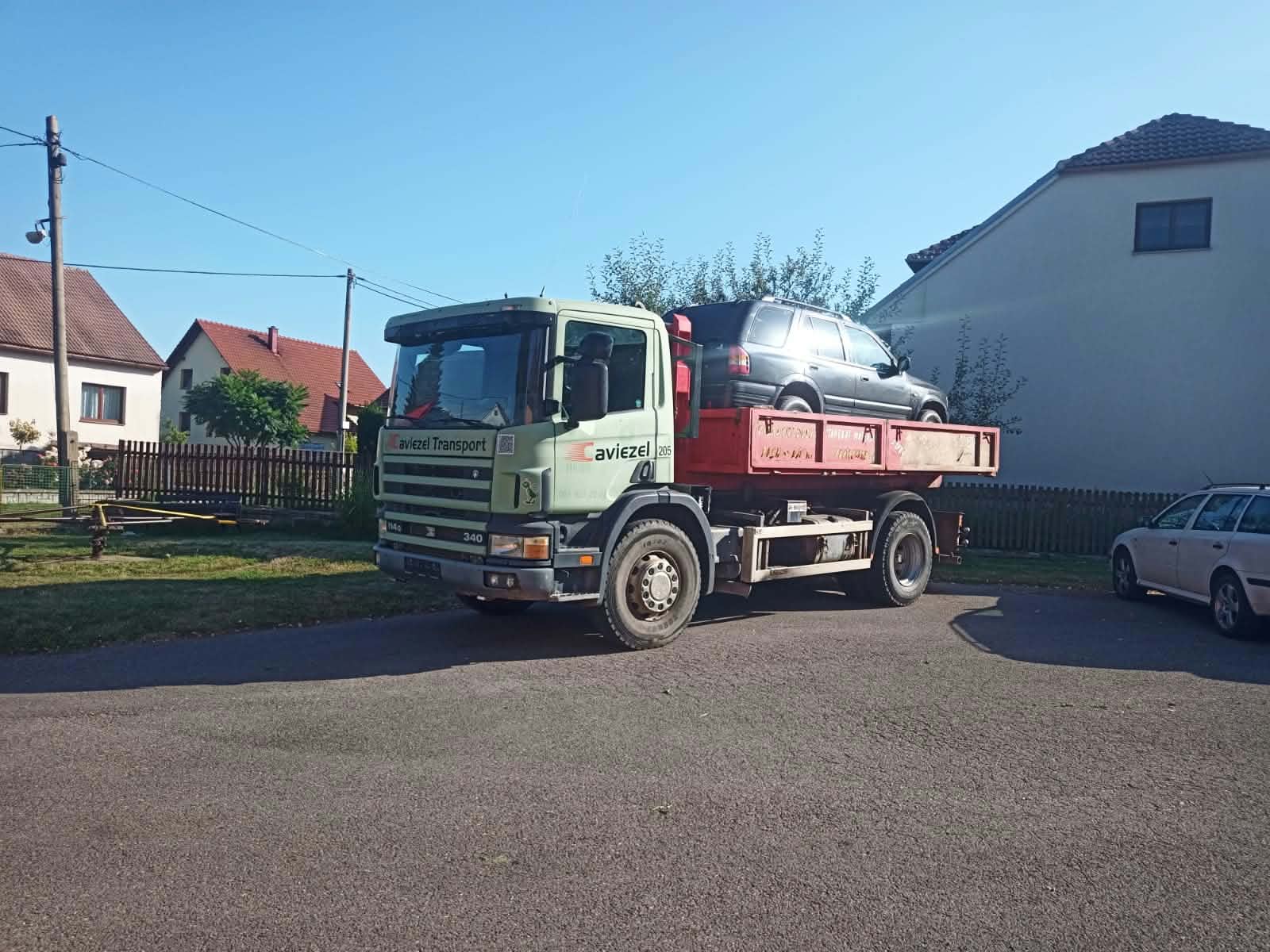 Nákladní auto převáží osobní vůz naložený na korbě