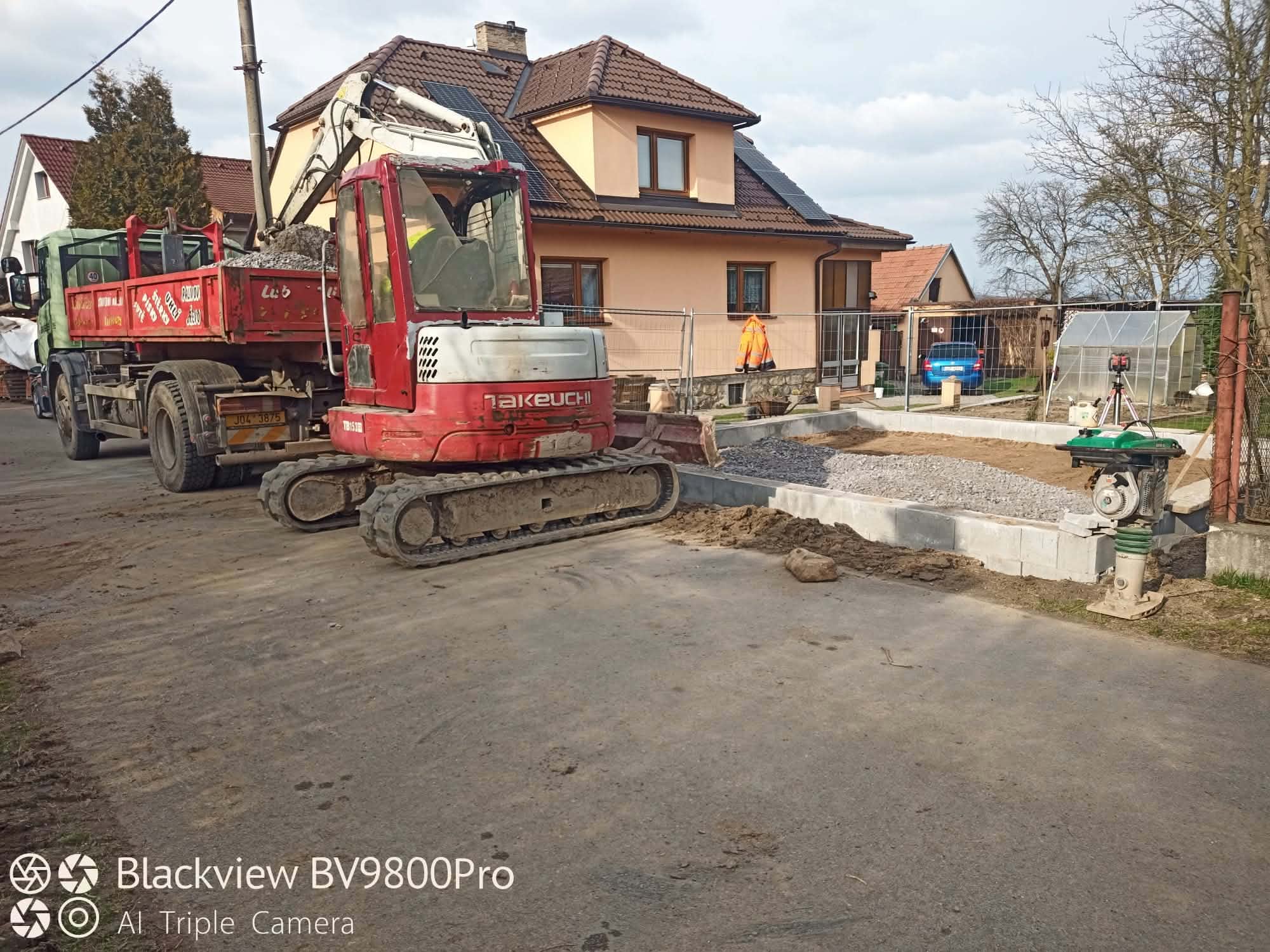 Minibagr Takeuchi a nákladní auto při přípravě zpevněné plochy u domu