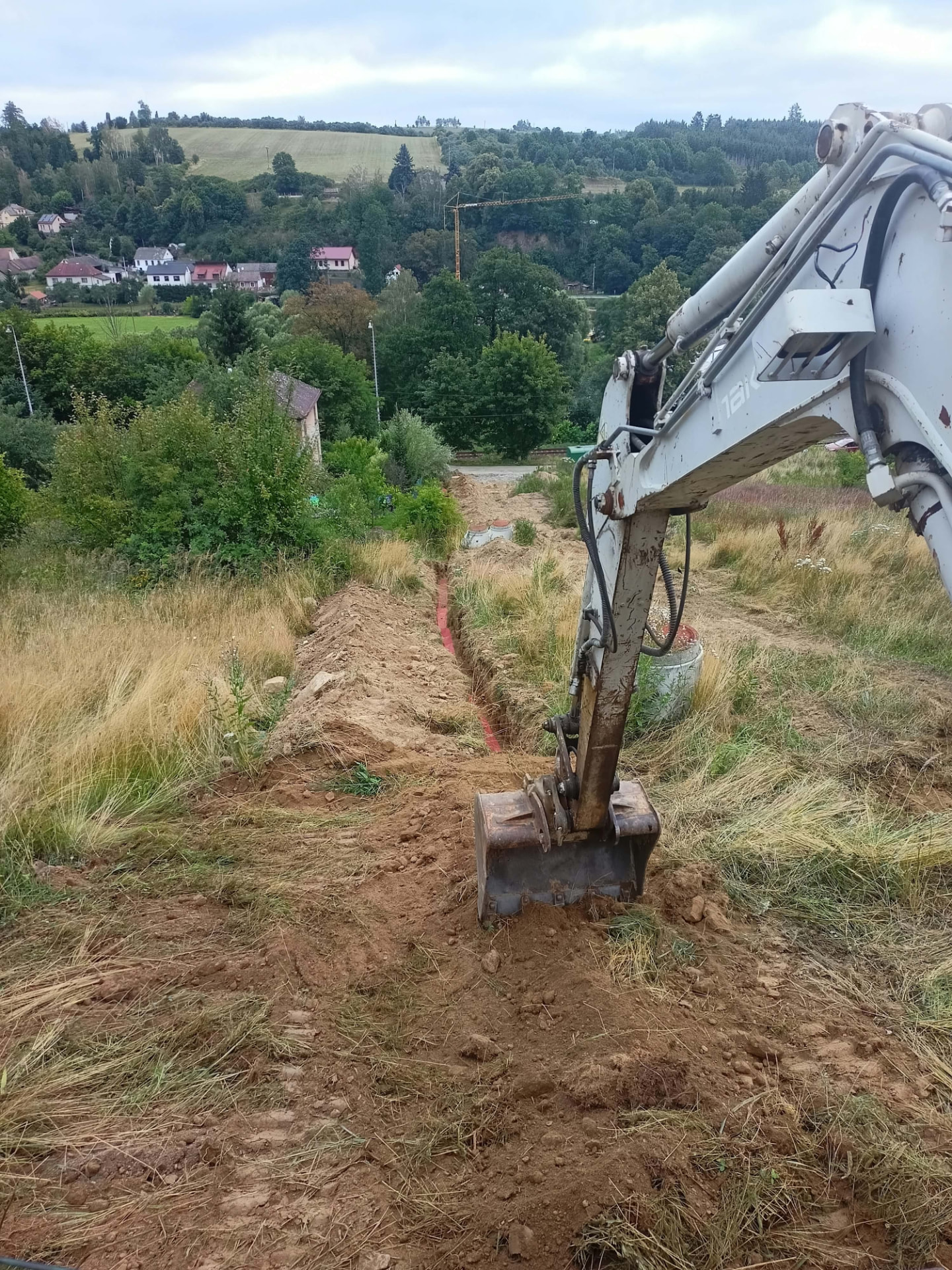 Rameno bagru u výkopu pro přípojku na svahu